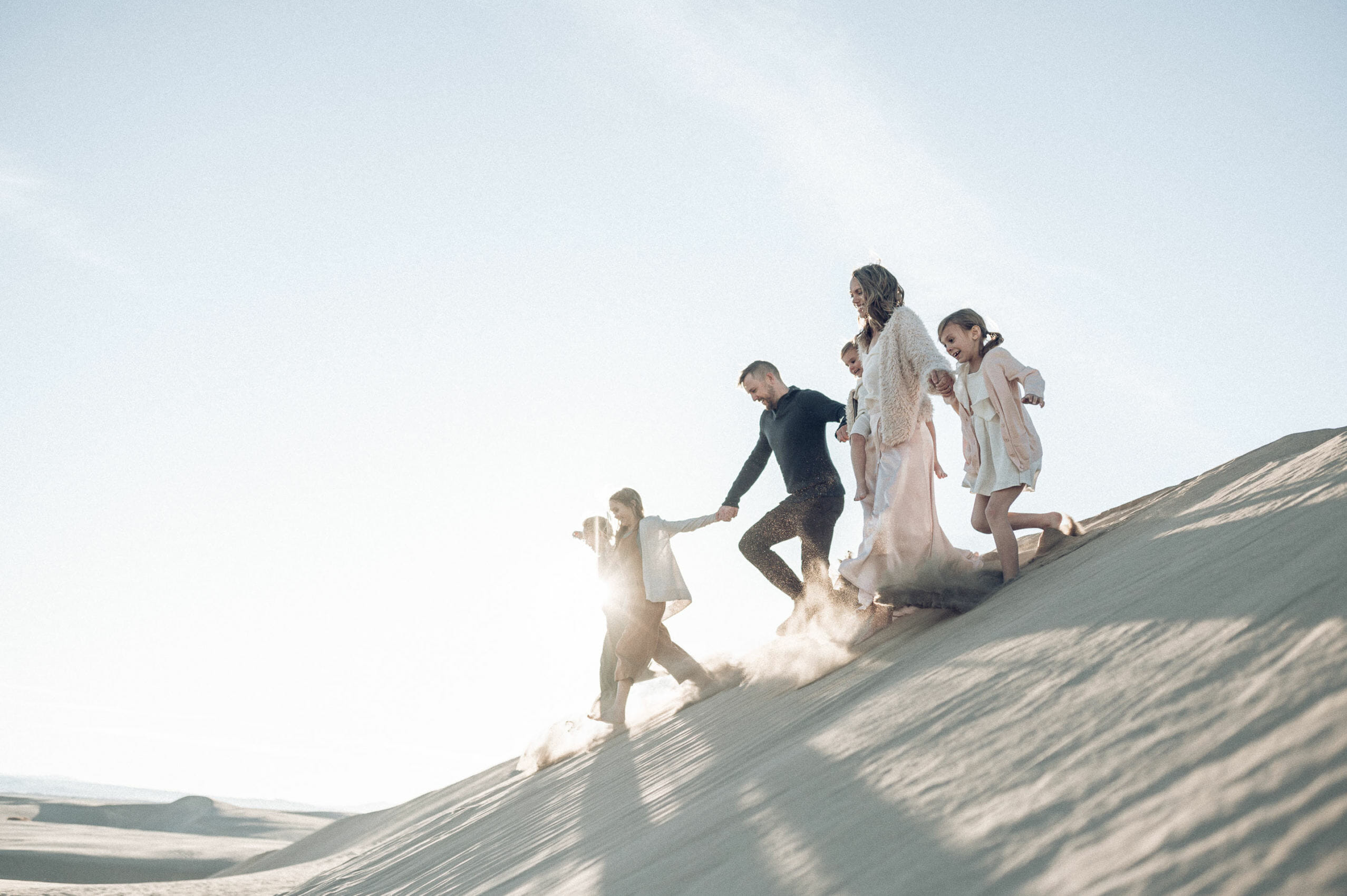 Family running on a sand dune