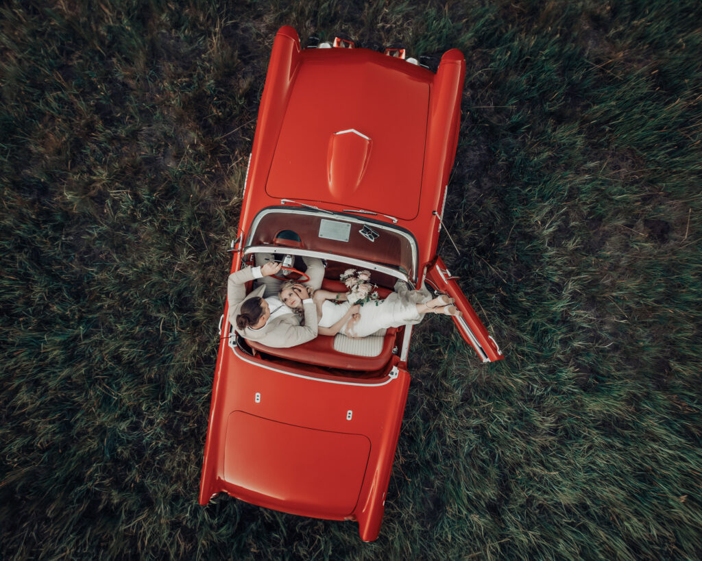 a couple photographed by a drone while they sit int heir classic car at Black Butte Ranch