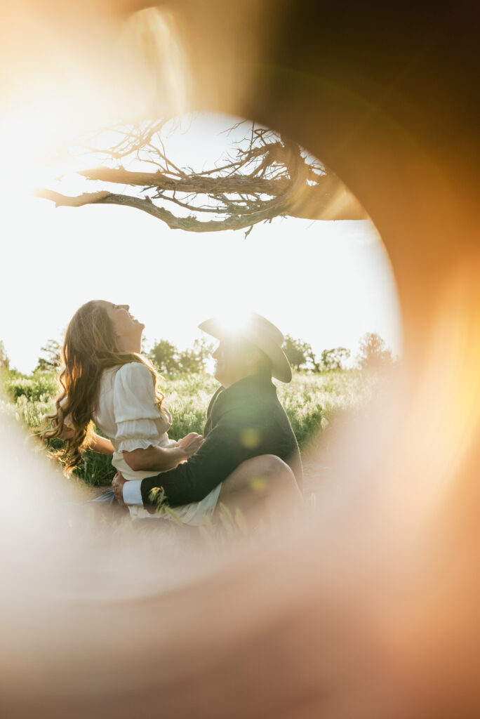 a couple laughing under a tree during an engagement shoot