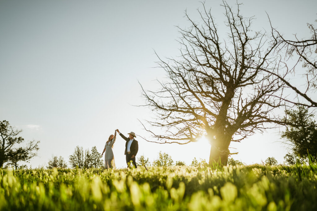 a couple twirling in the grass during their engagement session