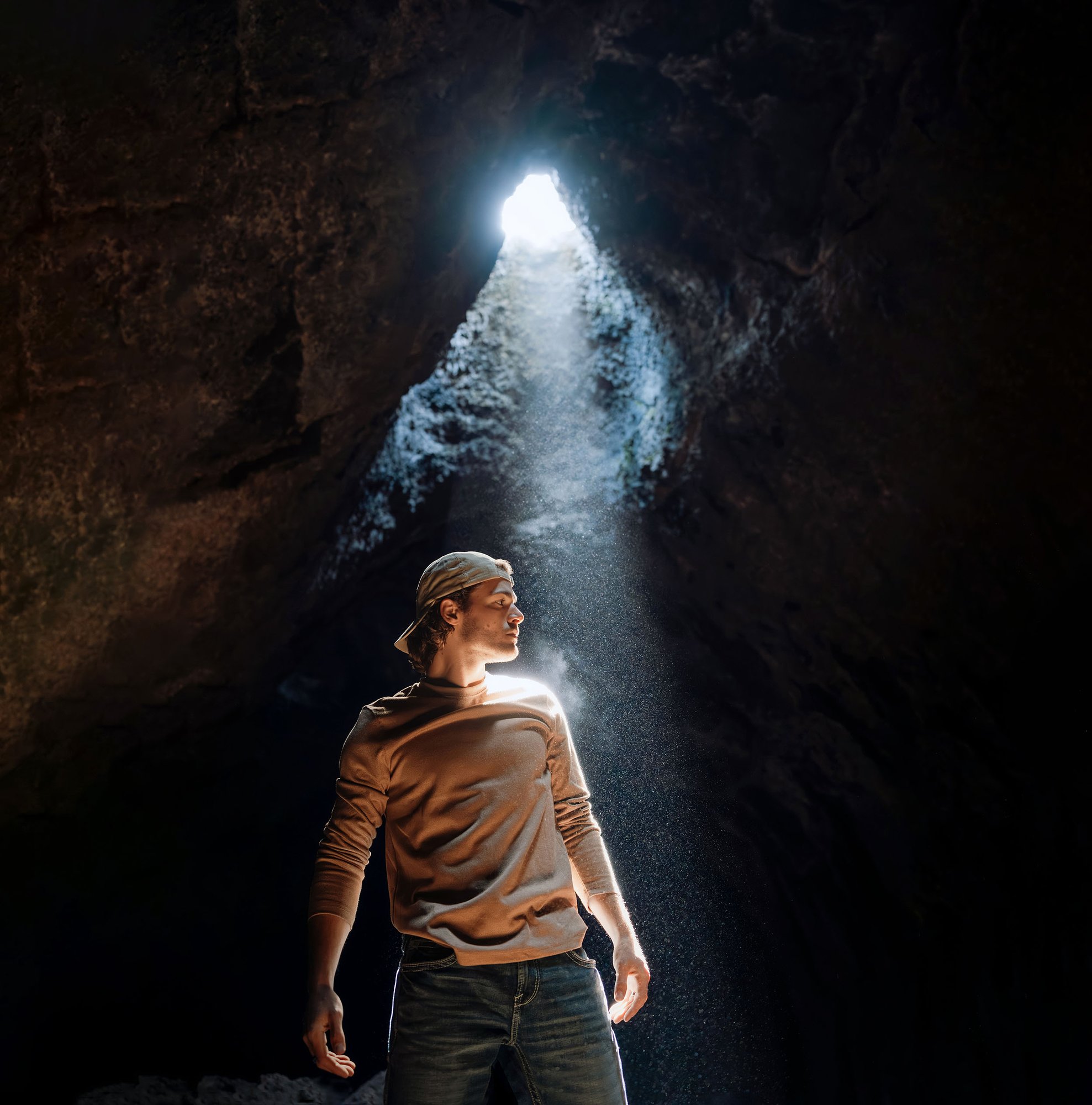 Max McNown Leave On A Light album cover — Max standing in a Central Oregon lava tube lit by a single shaft of daylight, photographed by Benjamin Edwards